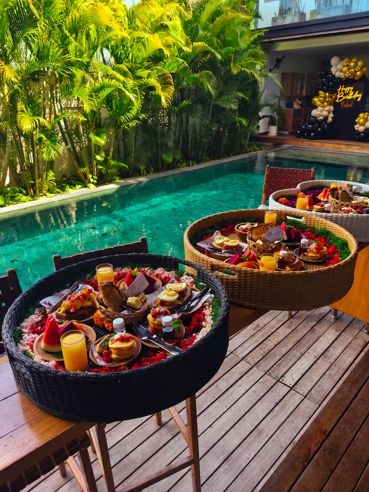 Floating breakfast trays beside a villa pool
